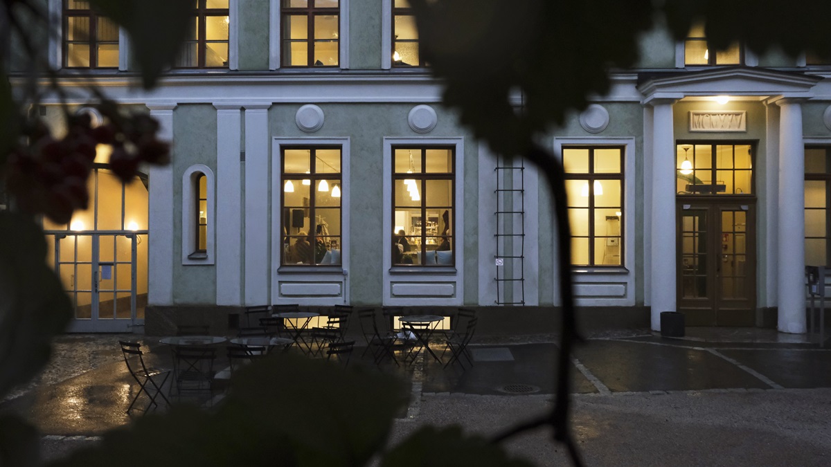 Hämärässä suuren kivitalon ikkunoista hohkaa lämmintä valoa.