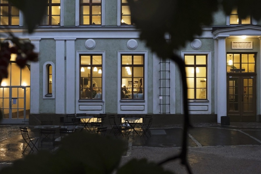 Hämärässä suuren kivitalon ikkunoista hohkaa lämmintä valoa.